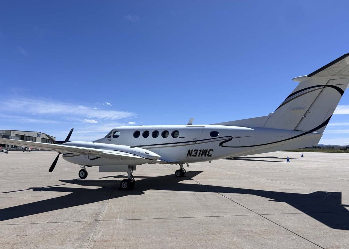 A white Beechcraft King Air N31WC parked on the tarmac under a blue sky.