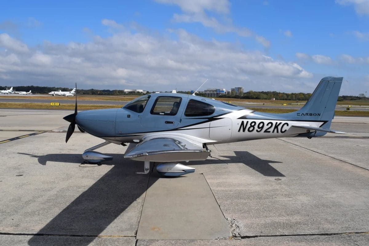 A Cirrus SR22T aircraft with a blue and silver paint scheme is parked on the tarmac.