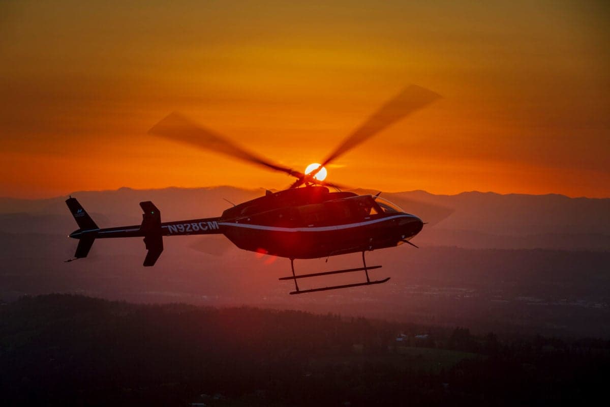 Helicopter N928CM flying at sunset.