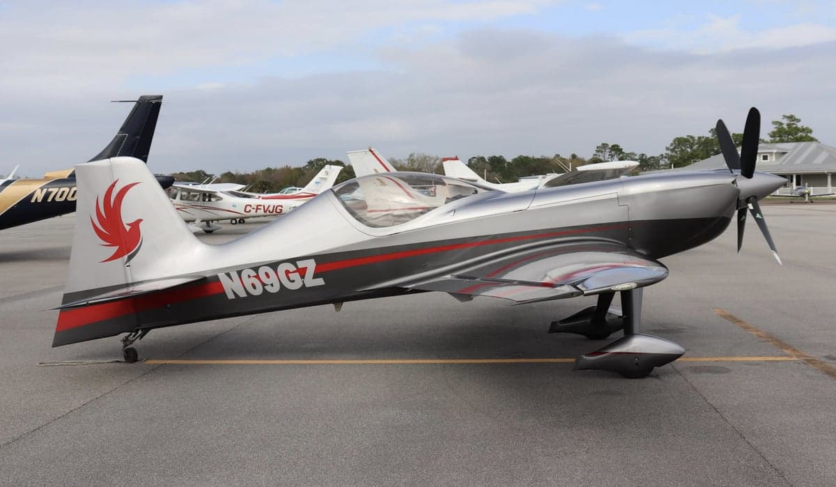 Single engine aircraft with silver and red paint scheme on the tarmac.