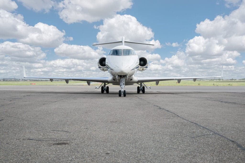 A Bombardier Challenger 350 aircraft is parked on the tarmac, viewed from the front.