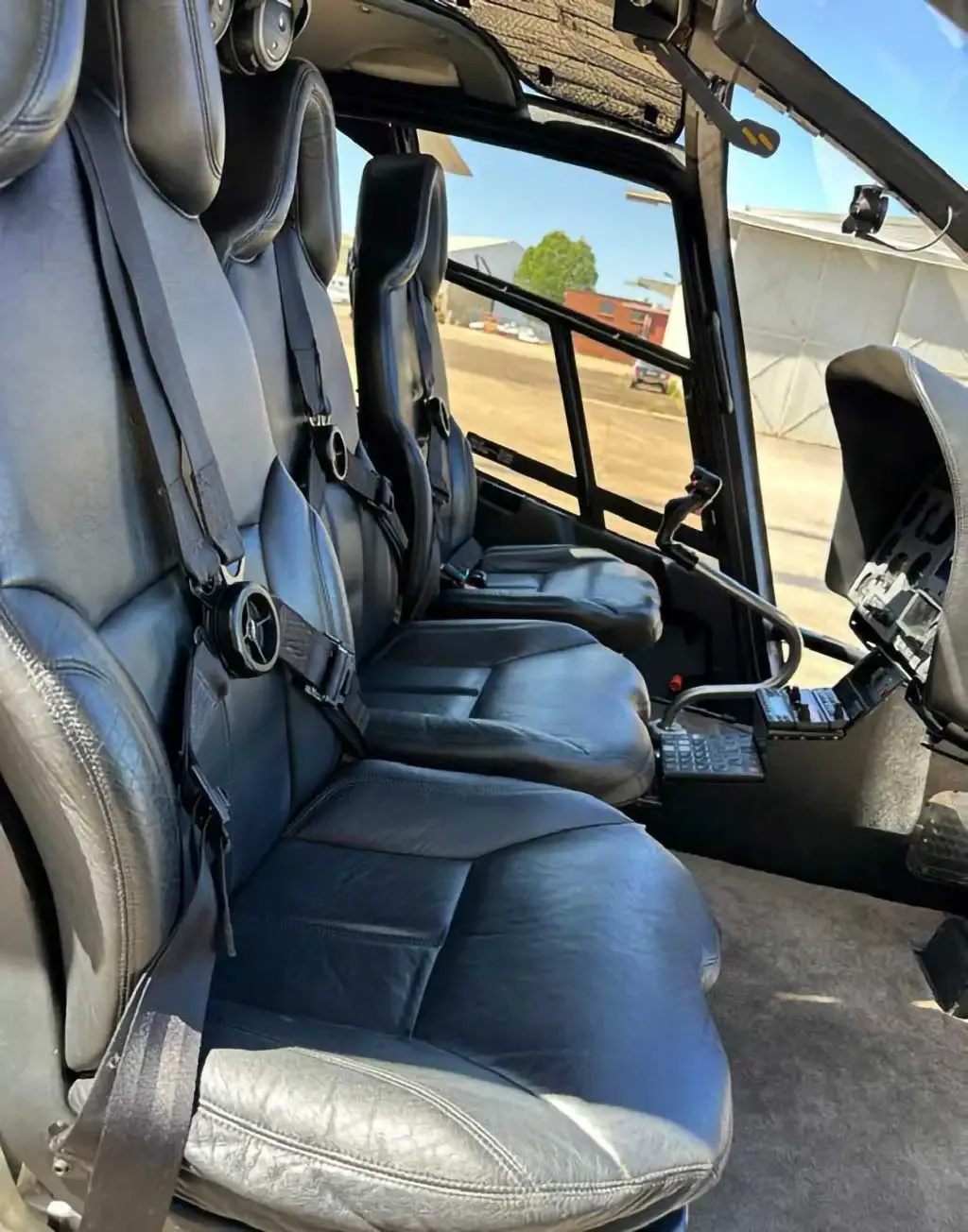 The helicopter's cockpit and front cabin area, showing black leather seats and flight controls.