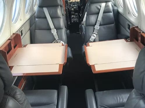 View of the aircraft's interior with leather seats and fold-out tables.