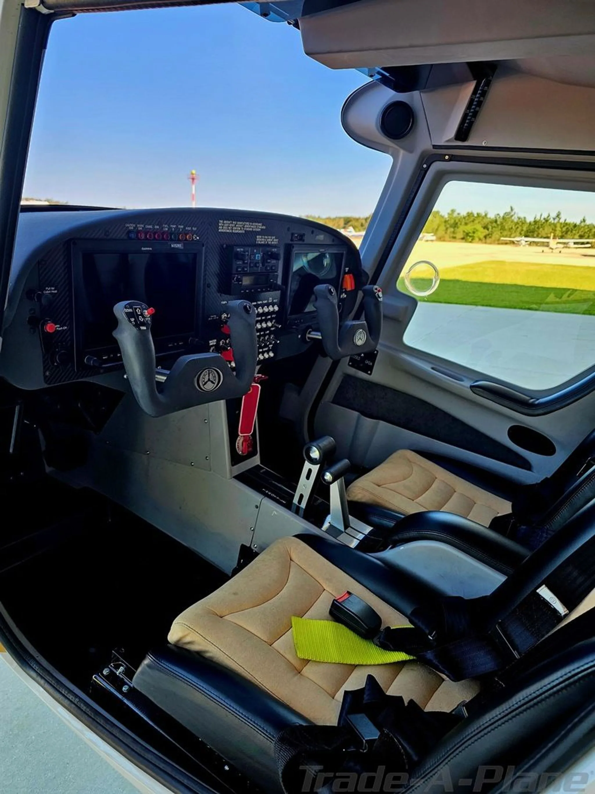 The cockpit of the I600 aircraft, showing the instrument panel, dual yokes, and tan and black seats.