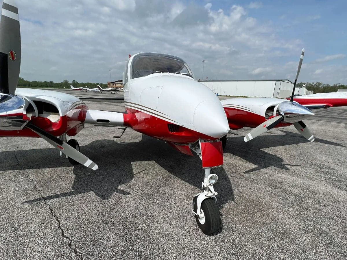 A front-quarter view of the N1242G twin-engine aircraft with its landing gear extended, on an airfield.
