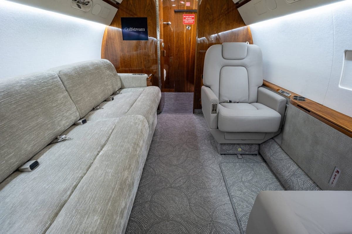 The aircraft's interior features a couch, seating, and wood trim.