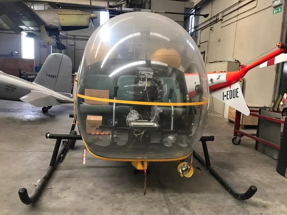 Side view of a yellow and white helicopter with a bubble canopy.