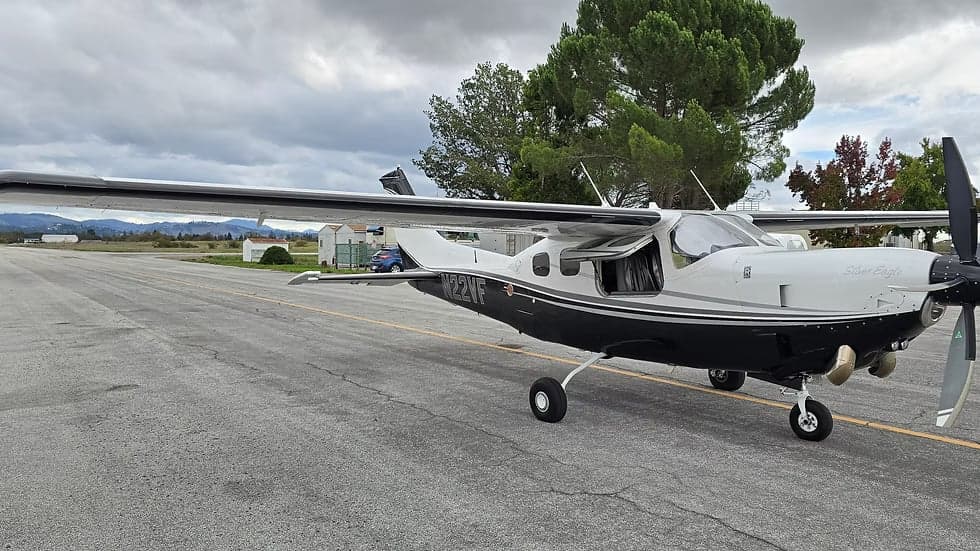 A black and white Cessna 208B Grand Caravan, registration N22VF, is parked on the tarmac with its door open.