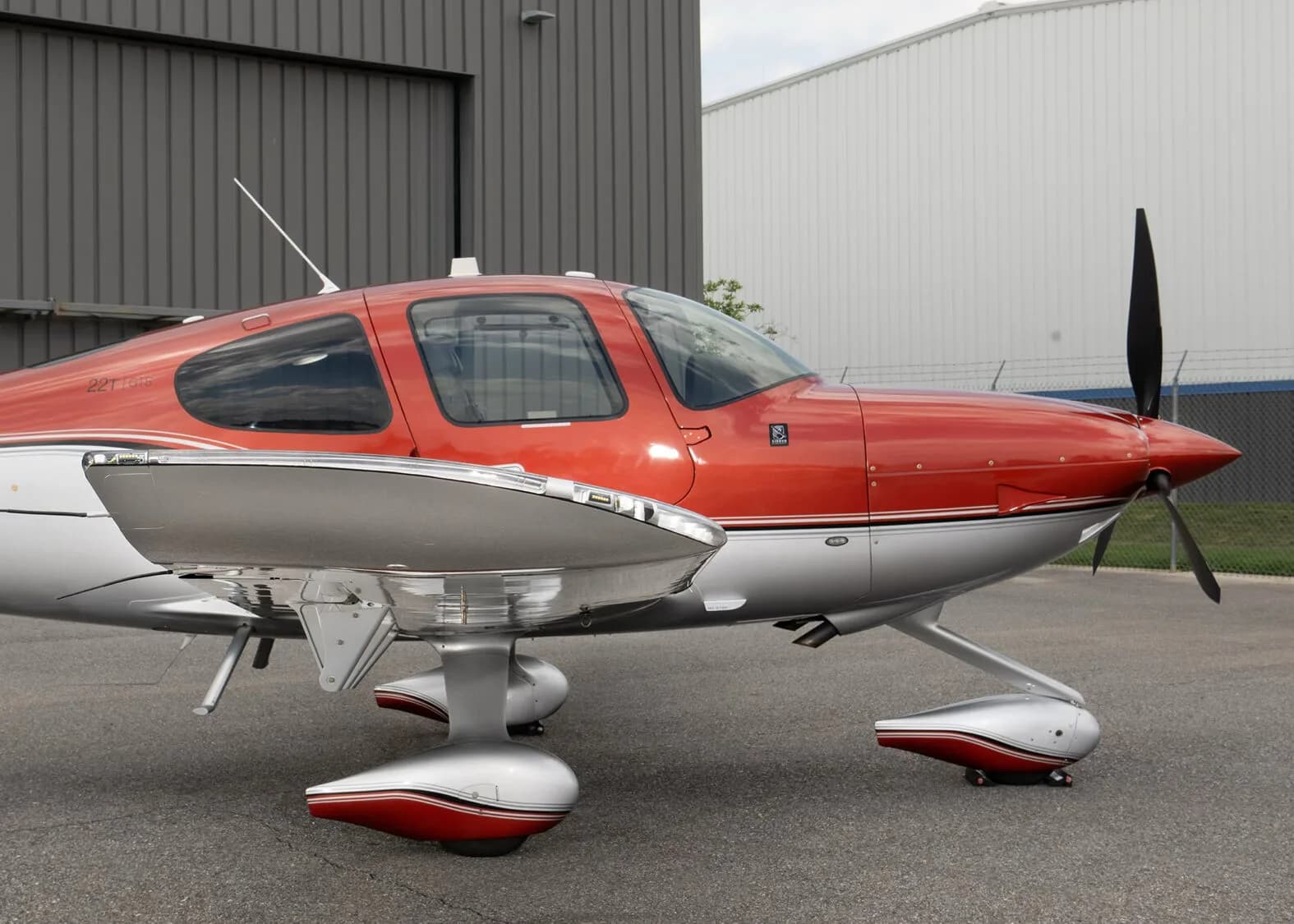 A close-up side view of the cockpit and front landing gear of the red and silver Cirrus SR22T aircraft, N96KJ.