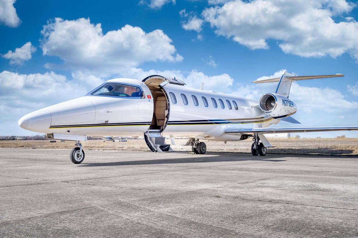 A Learjet 75 Liberty is parked on the tarmac with its door open.
