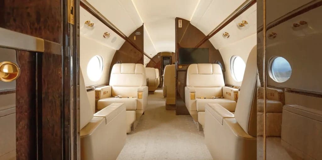 Interior view of the aircraft cabin with beige leather seats and wood trim.