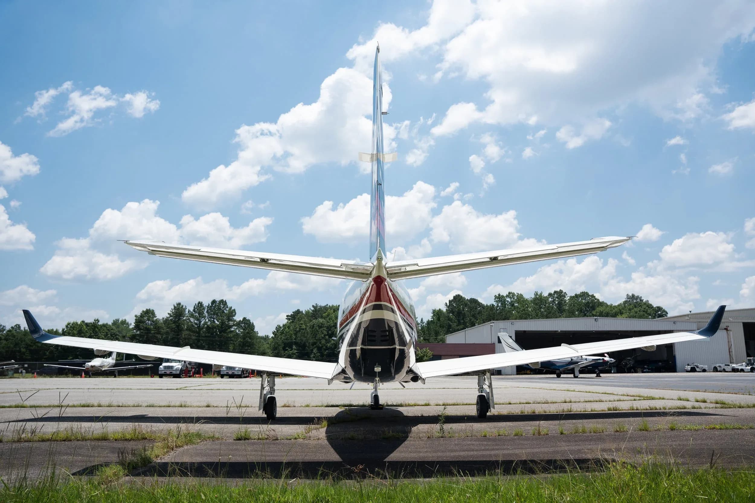 A rear view of a white and black TBM 960 aircraft with its tail and wings prominent, parked on an airport tarmac.