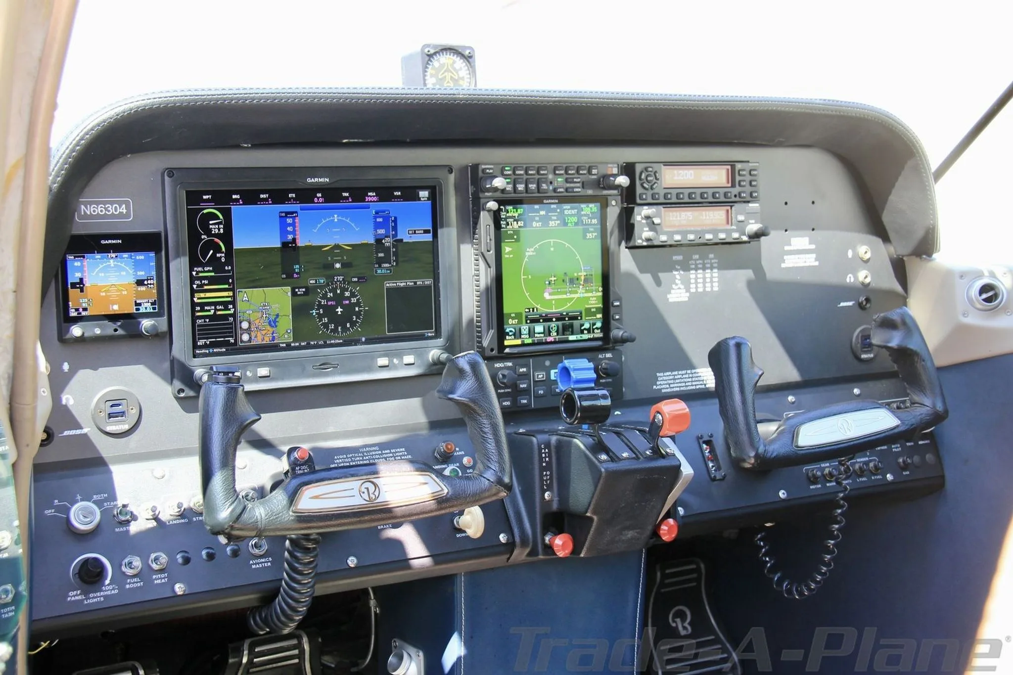 The modern glass cockpit of aircraft N66304, featuring multiple Garmin displays and dual yokes.