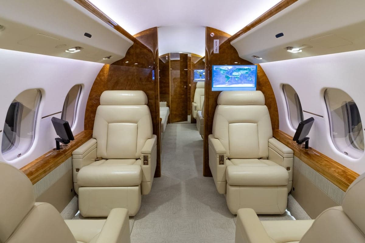 A view of the aircraft's interior with cream-colored leather seats and wood trim.