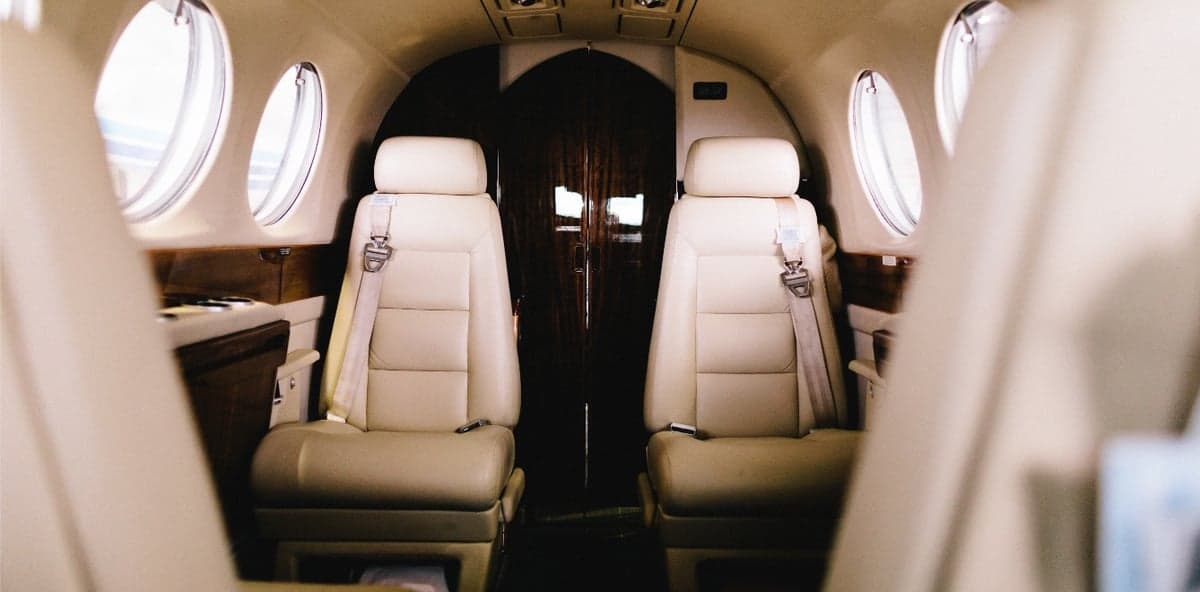 Interior view of the aircraft cabin with leather seats and a wooden partition.