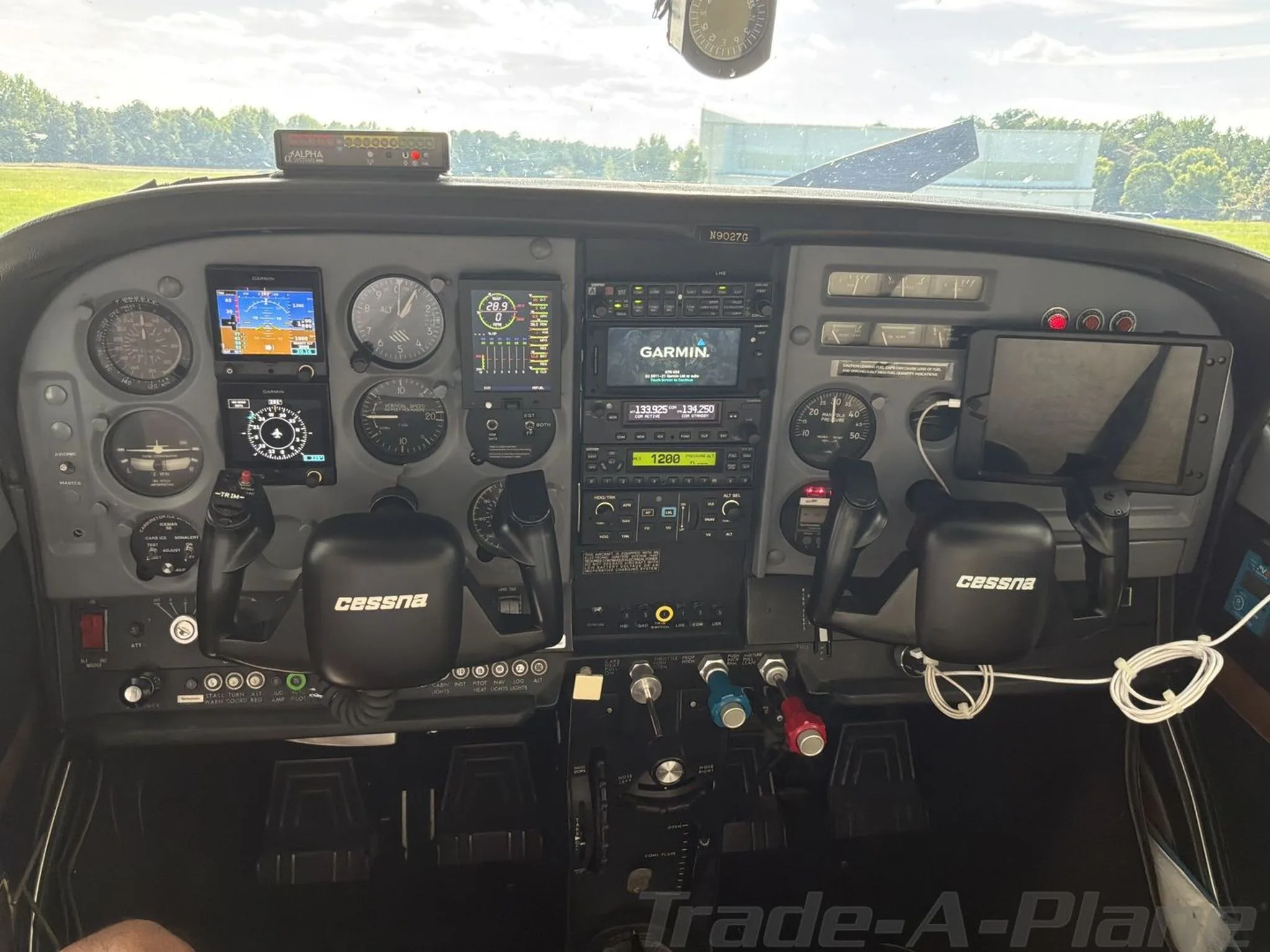 The cockpit of a Cessna 182N Skylane, showing the instrument panel with Garmin avionics screens illuminated.