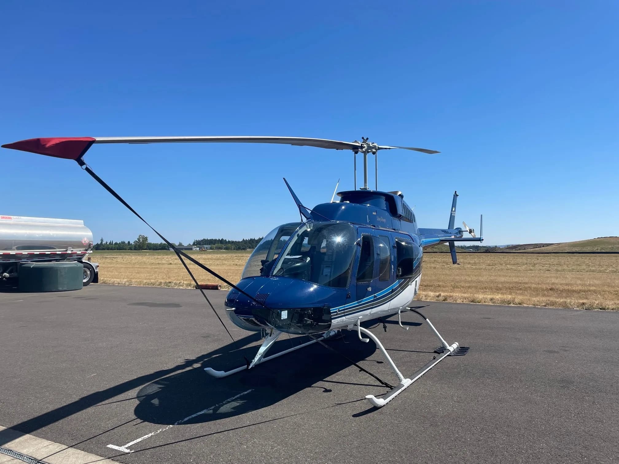 Bell 206B Jet Ranger with blue and white paint scheme, parked on the tarmac.