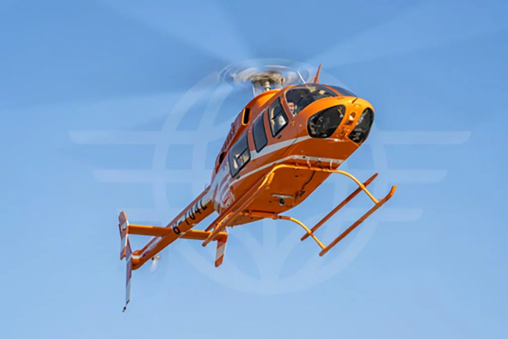 An orange Bell 407 helicopter with white stripes in flight against a clear blue sky, viewed from the front-left.
