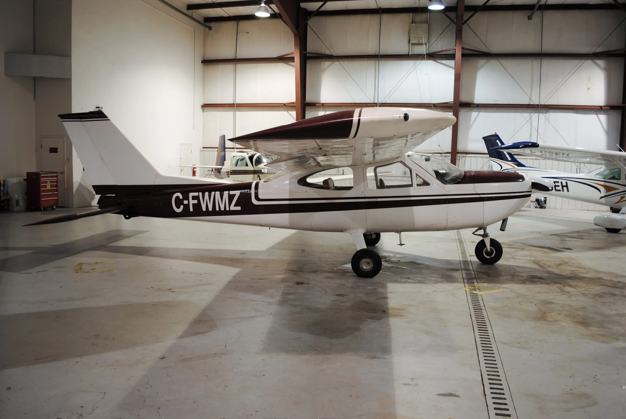 Side view of a Cessna 177 Cardinal with the registration C-FWMZ, parked in a hangar.