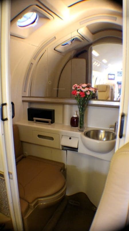 View of the aircraft lavatory with a sink, mirror, and toilet.