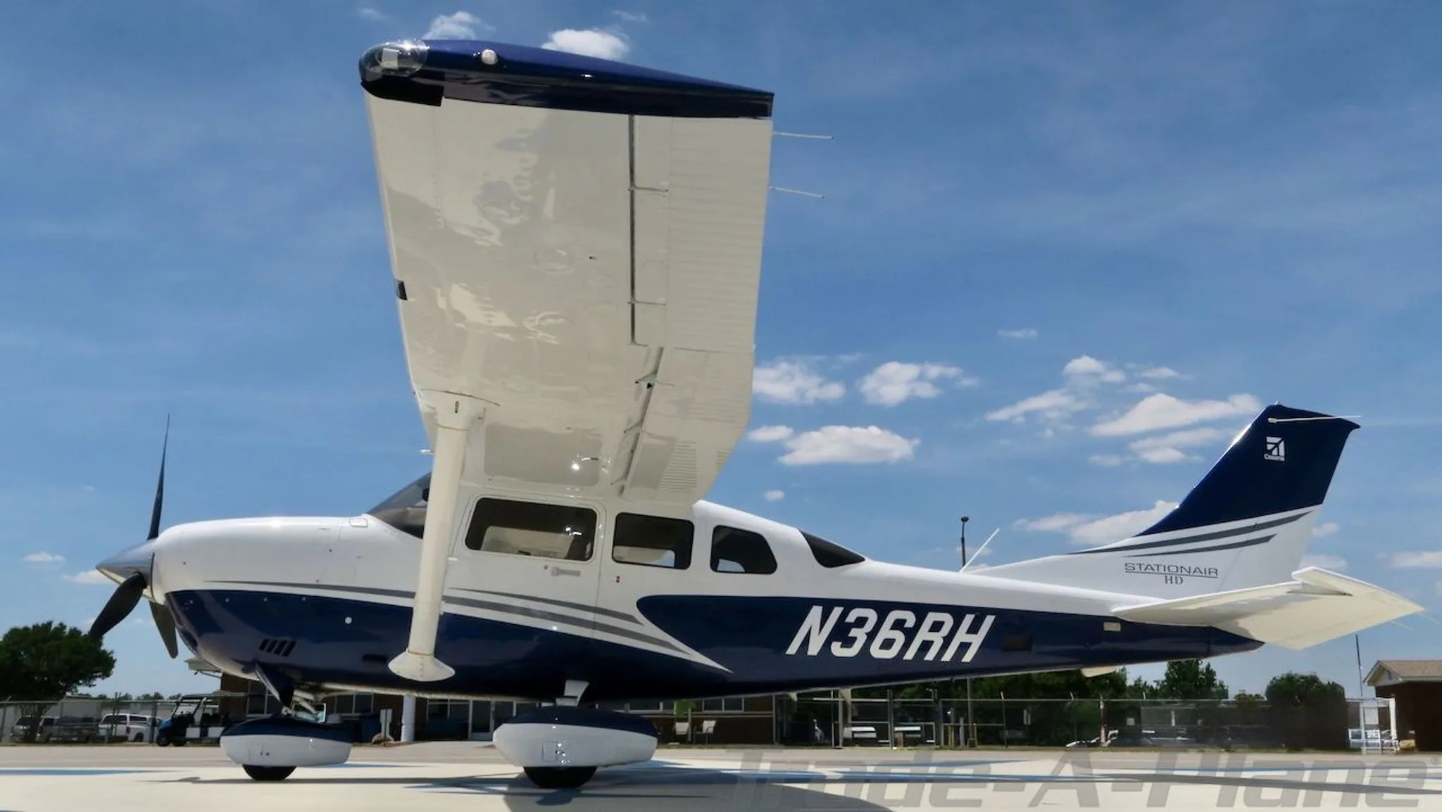 Rear-right view of a white and blue Cessna Stationair HD (N36RH) on an airfield.