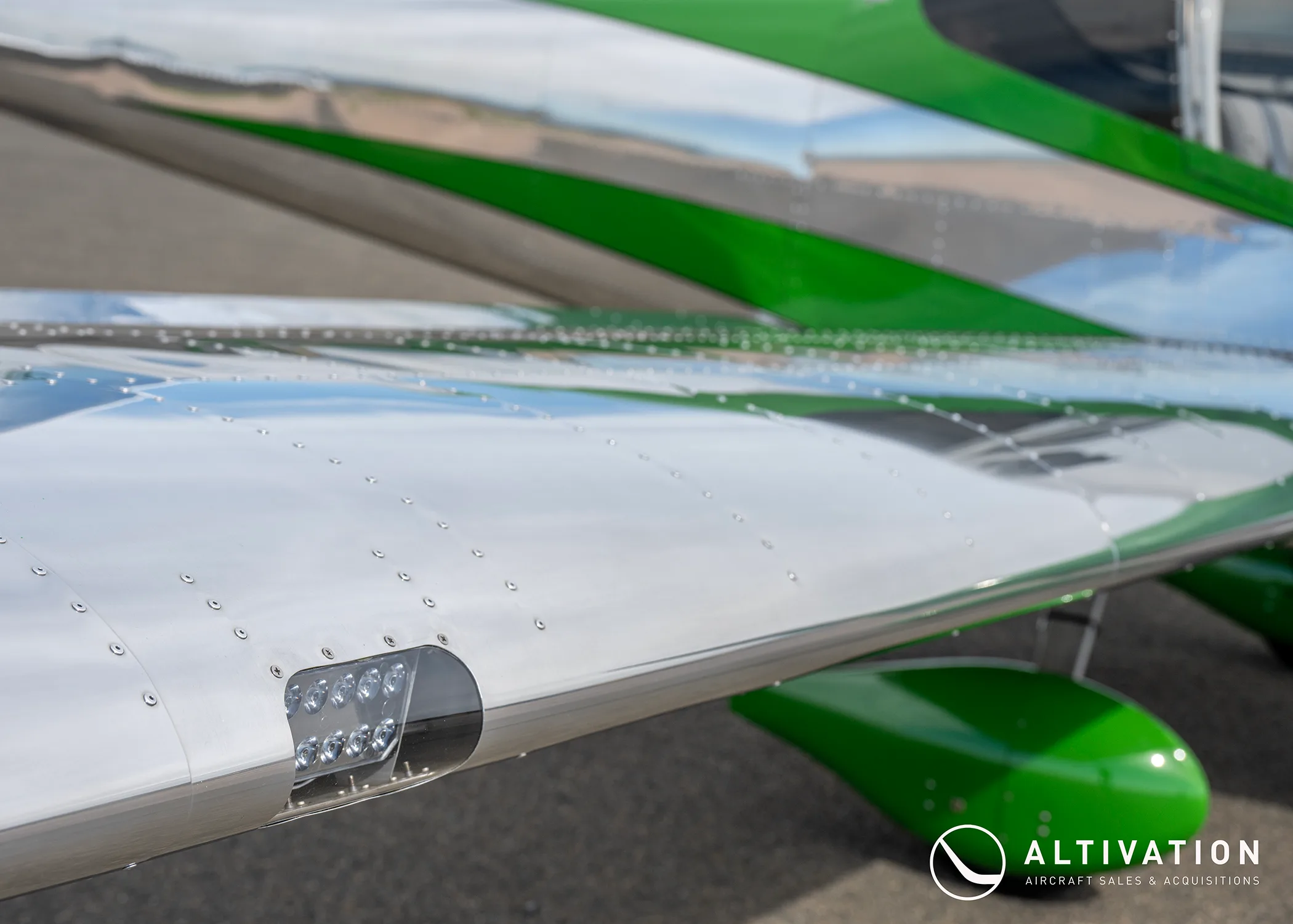 A close-up of the polished aluminum wing and green landing gear fairing of a Vans RV-12 aircraft.