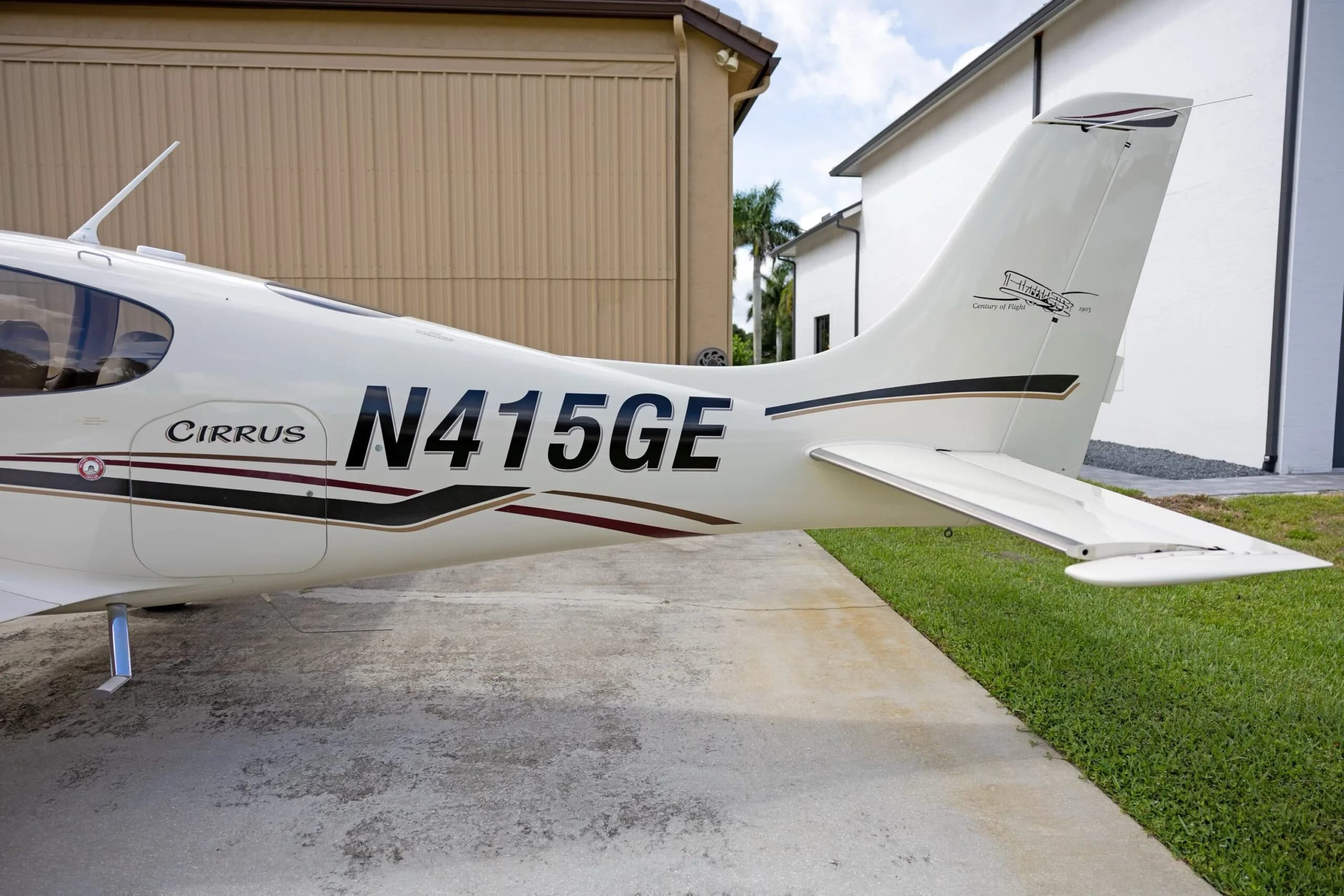 A close-up view of the tail section of a white Cirrus SR22 aircraft, showing registration N415GE and 'Century of Flight' logo.