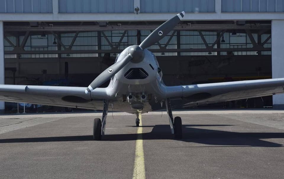 Front view of the aircraft on the tarmac in front of a hangar.