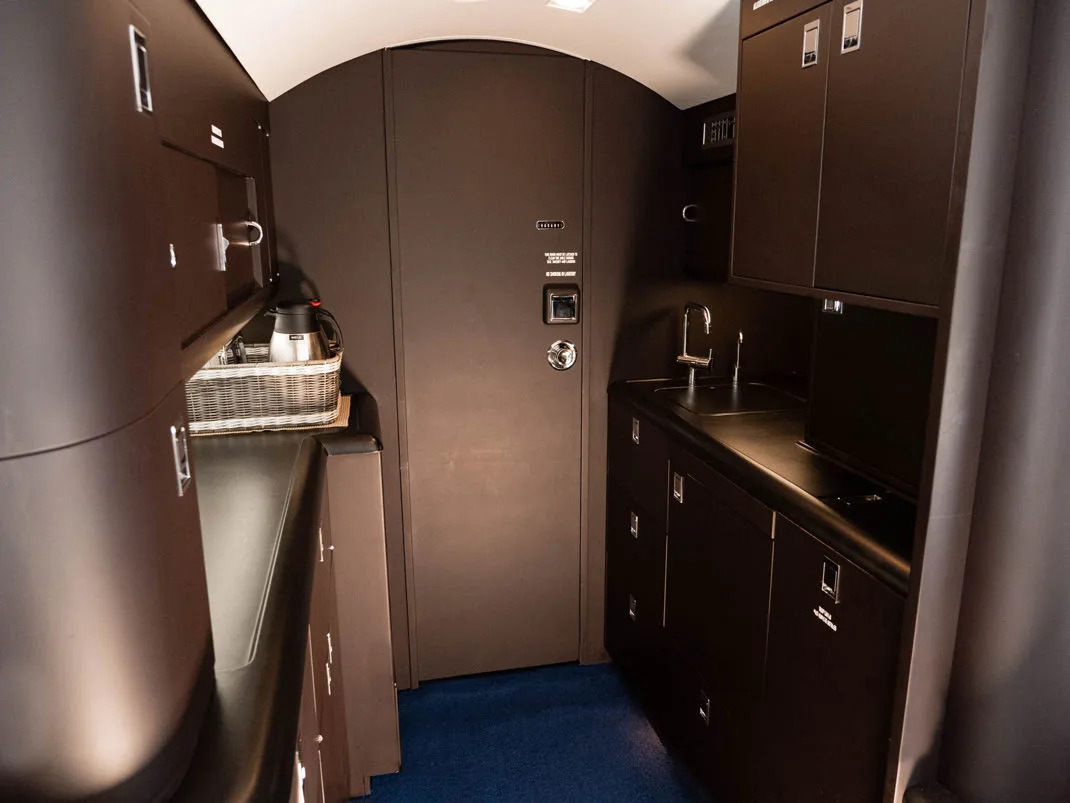 View of the aircraft galley with dark wood cabinets and a sink.