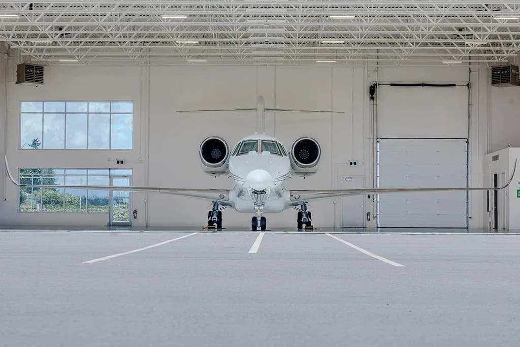 A white business jet, registration C-FJDM, seen from the front, parked inside a hangar.