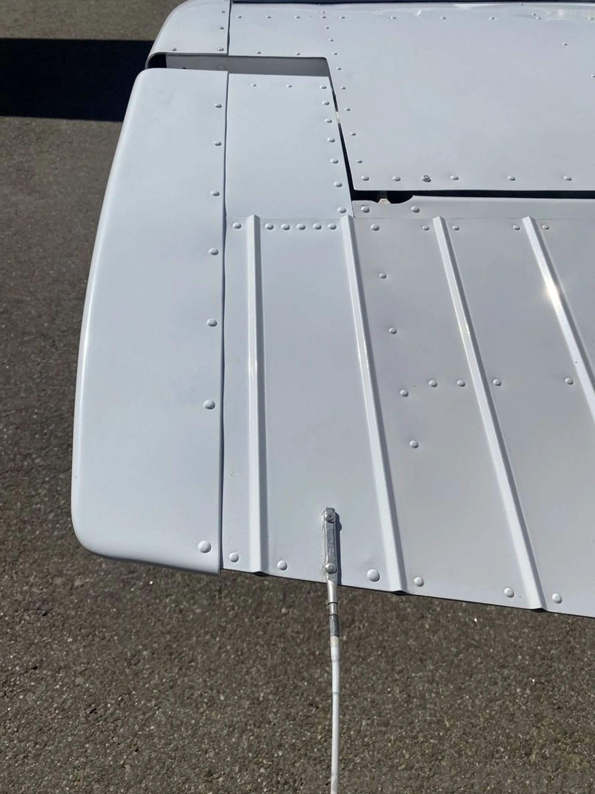 A close-up view of the riveted surface of a white aircraft wing.