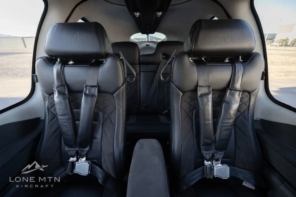 View looking forward from the rear seats, showing the black leather front and rear seats with quilted stitching.
