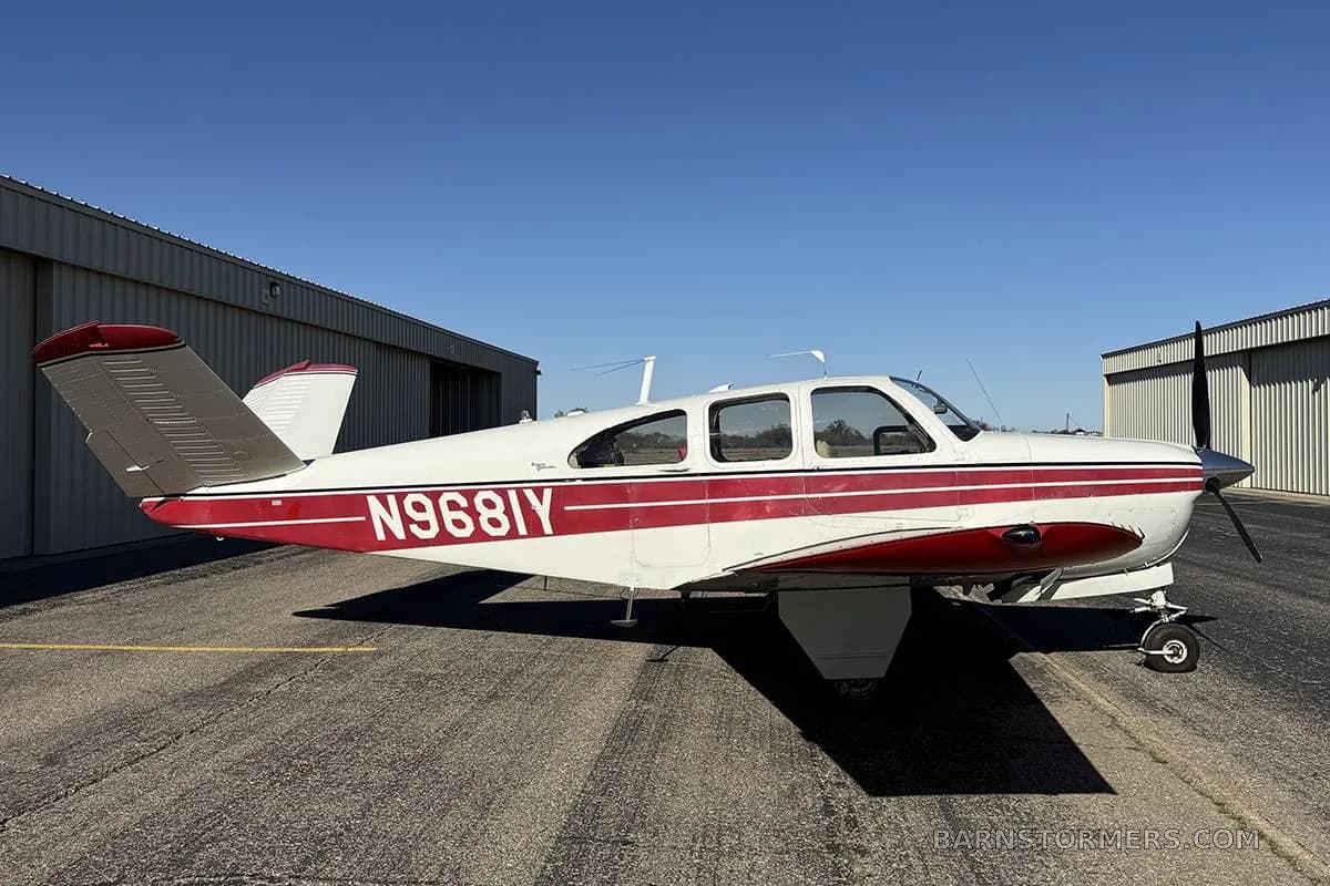 A white single-engine aircraft with red stripes and registration N968IY viewed from the right side on a tarmac.