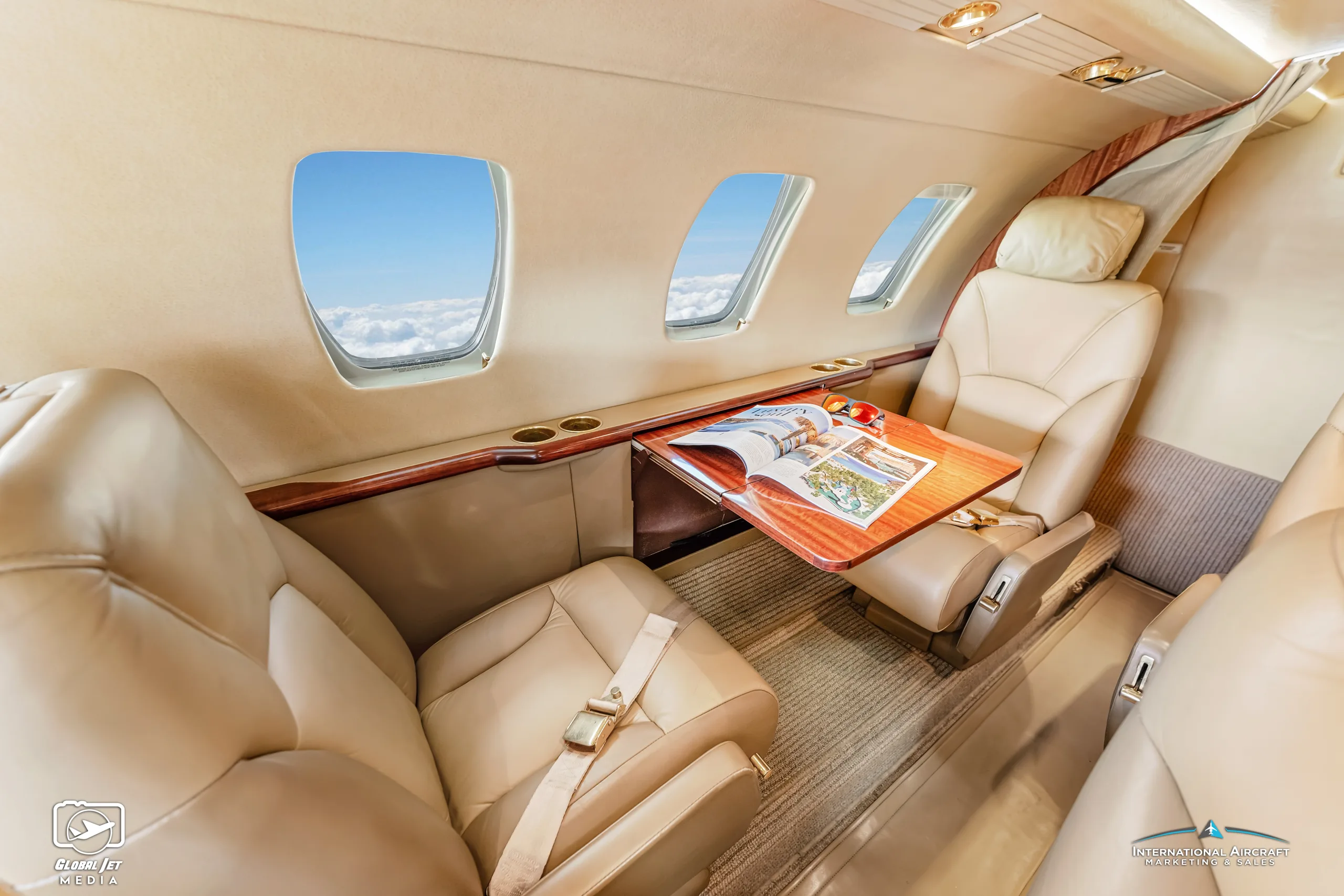 Interior of a Cessna Citation CJ1 with tan leather seats and a wood table.