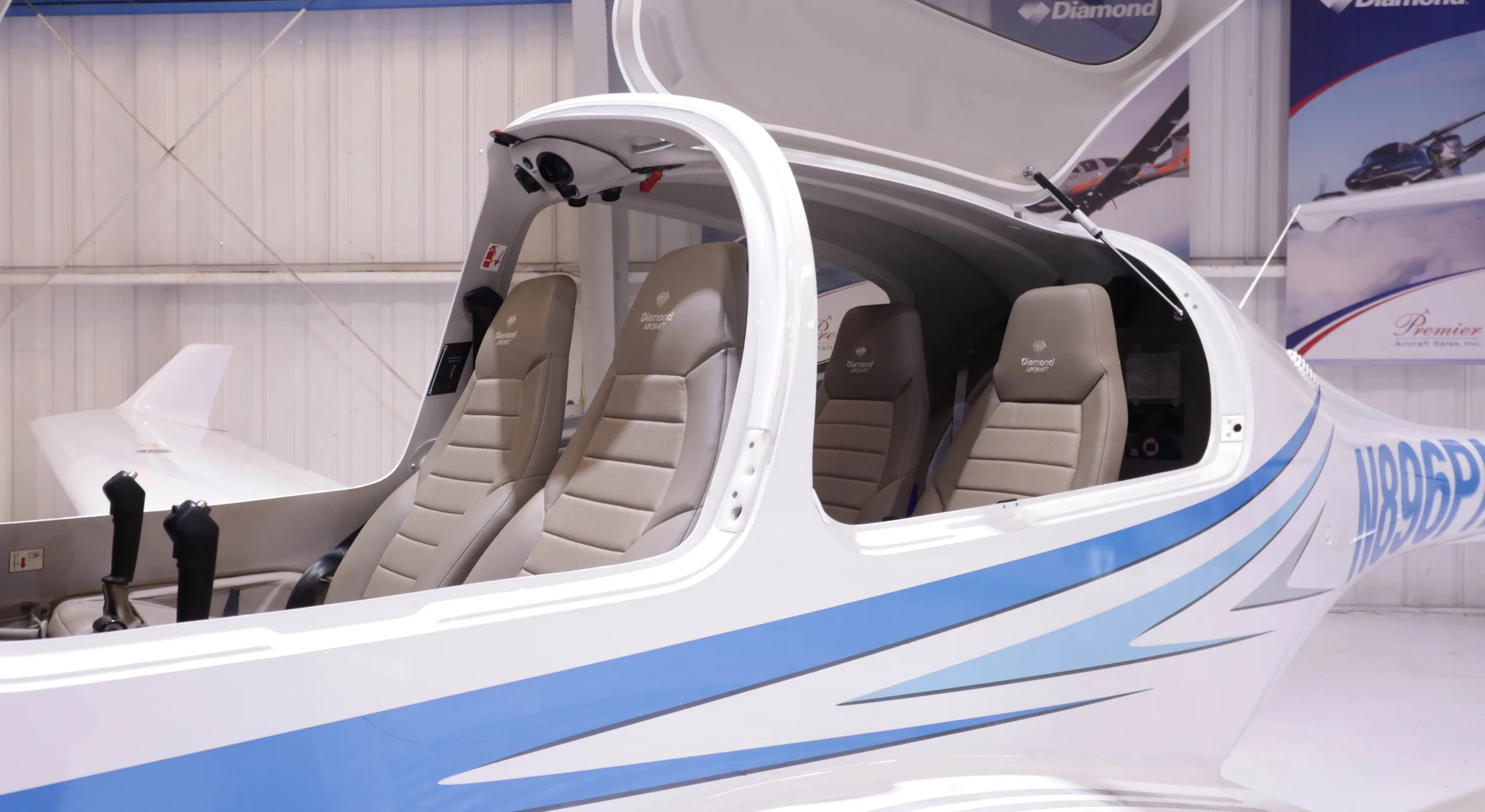 The interior cabin of a Diamond DA40 aircraft, showing three tan seats and the open canopy.
