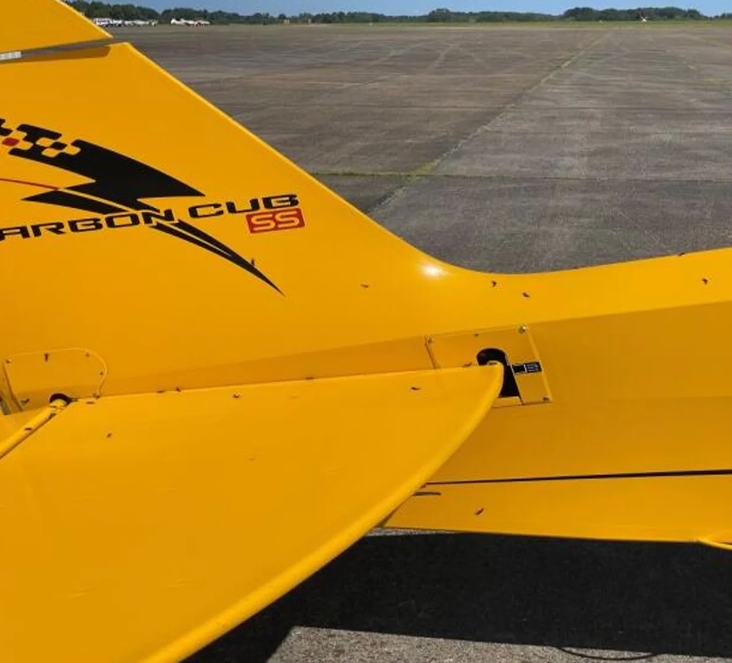 Close up of the tail of a yellow Carbon Cub aircraft with a black lightning bolt design.