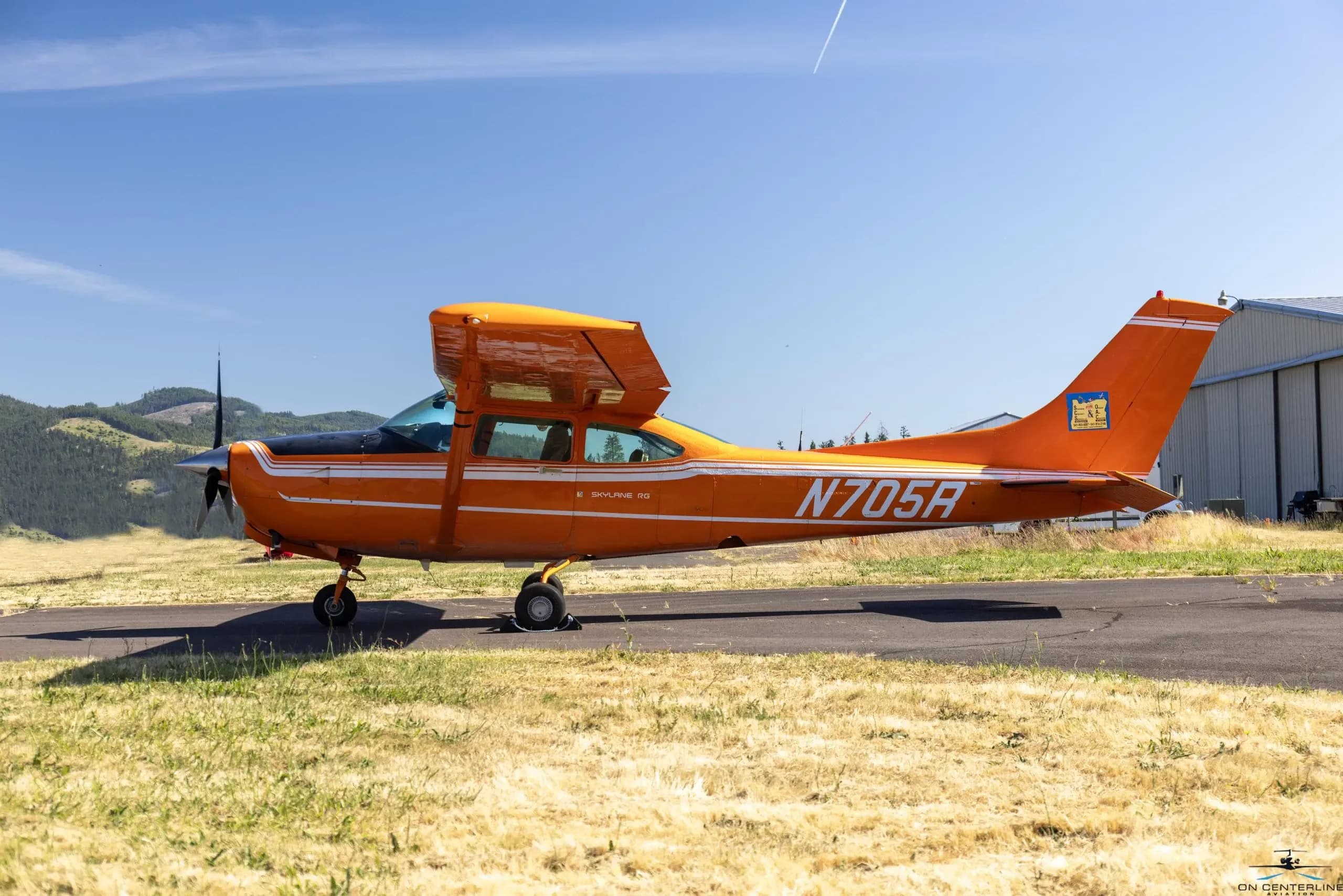 A Cessna 182 Skylane RG, tail number N705R, is parked on the tarmac.