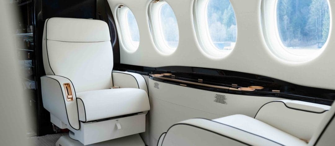 A close-up of the aircraft's interior with white leather seats and windows.