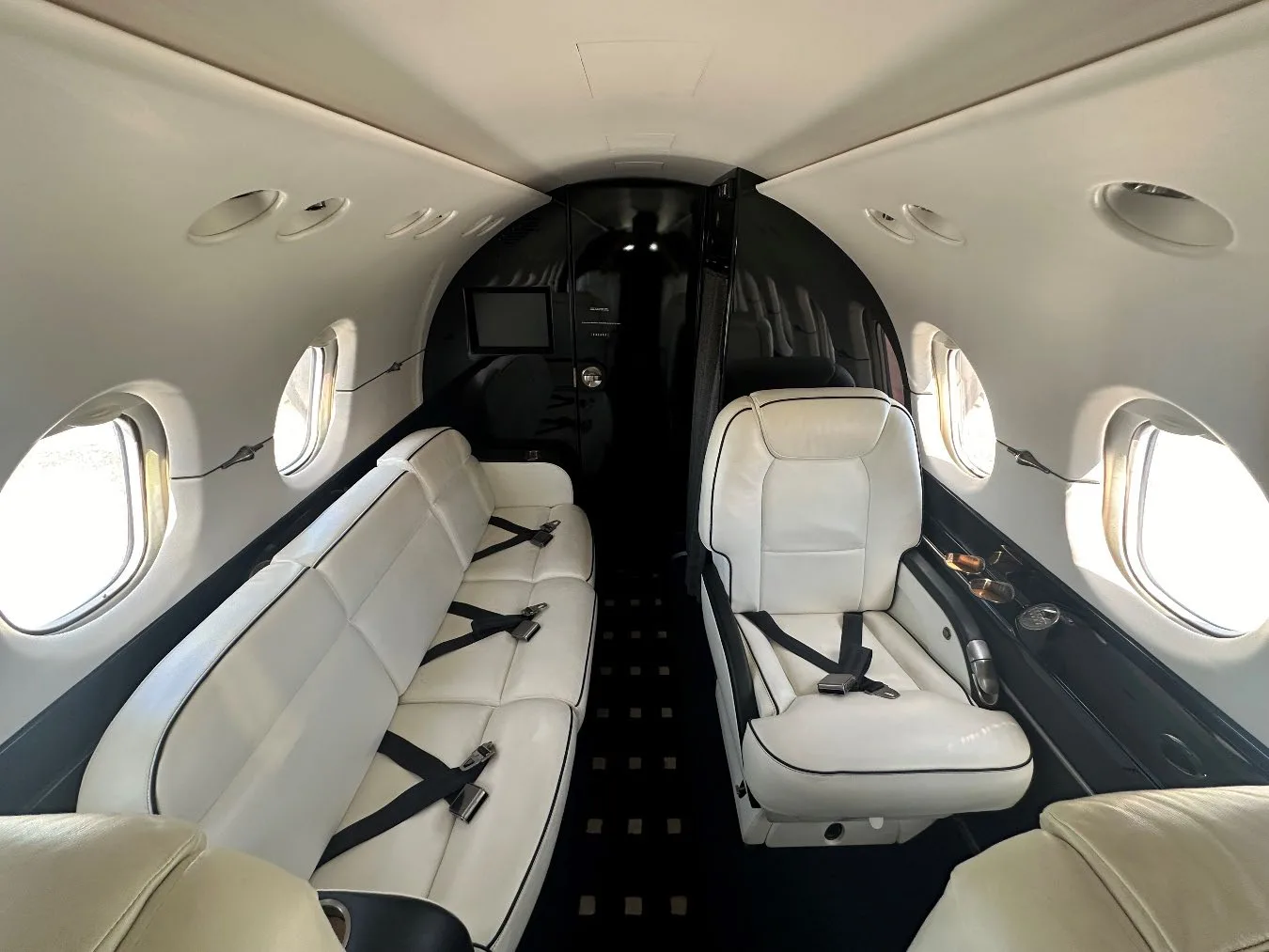 Interior view of the Hawker 400XP cabin with a white leather divan and seat.