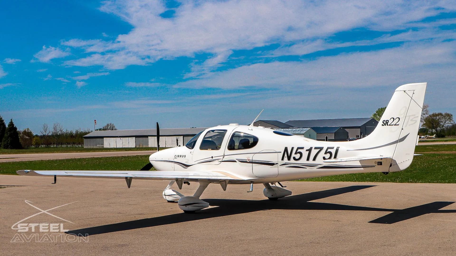Right side view of a white Cirrus SR22 aircraft (N5175L) with black and grey stripes, parked on an airfield.