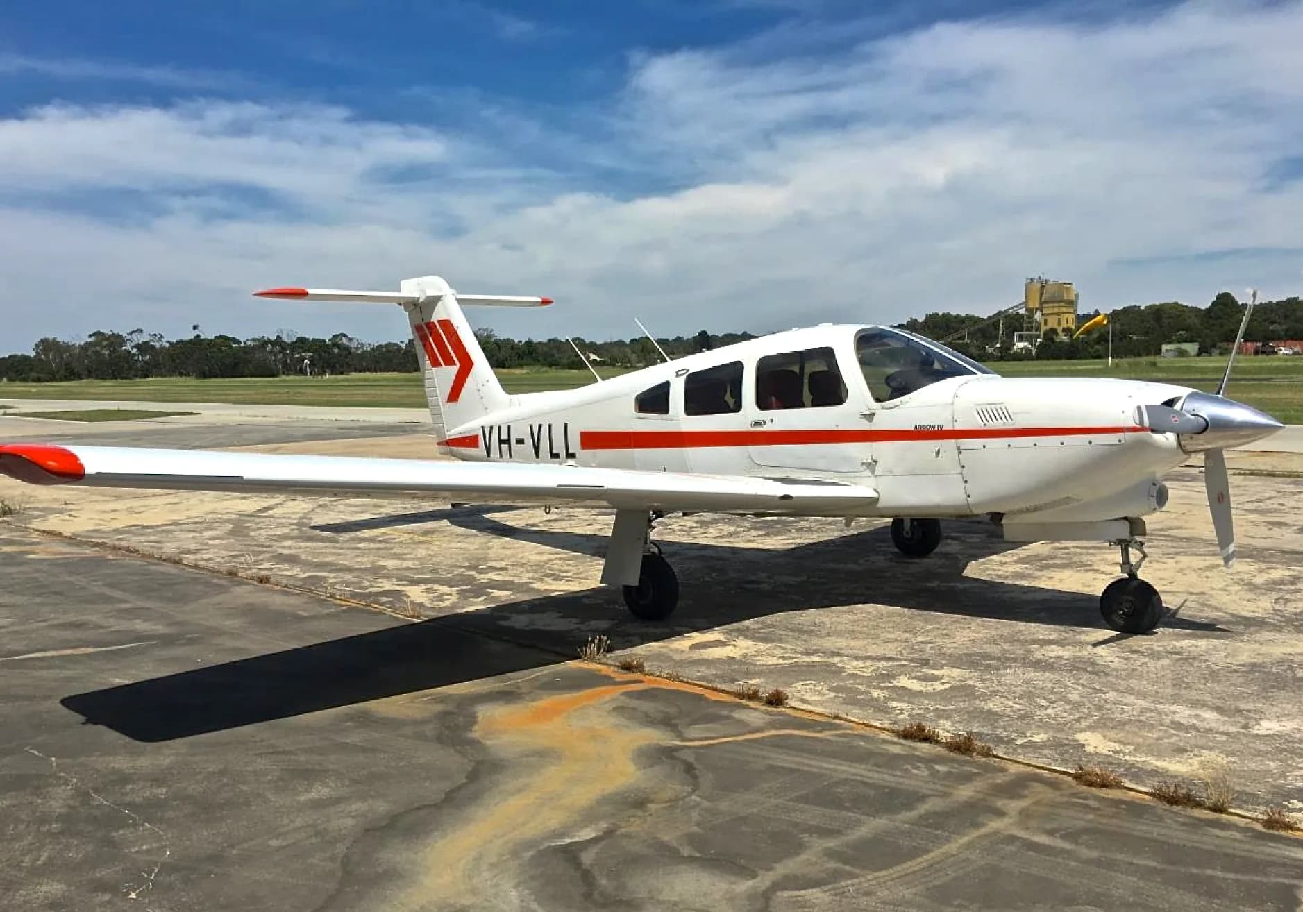 A white and red Piper Archer II aircraft is parked on the tarmac.