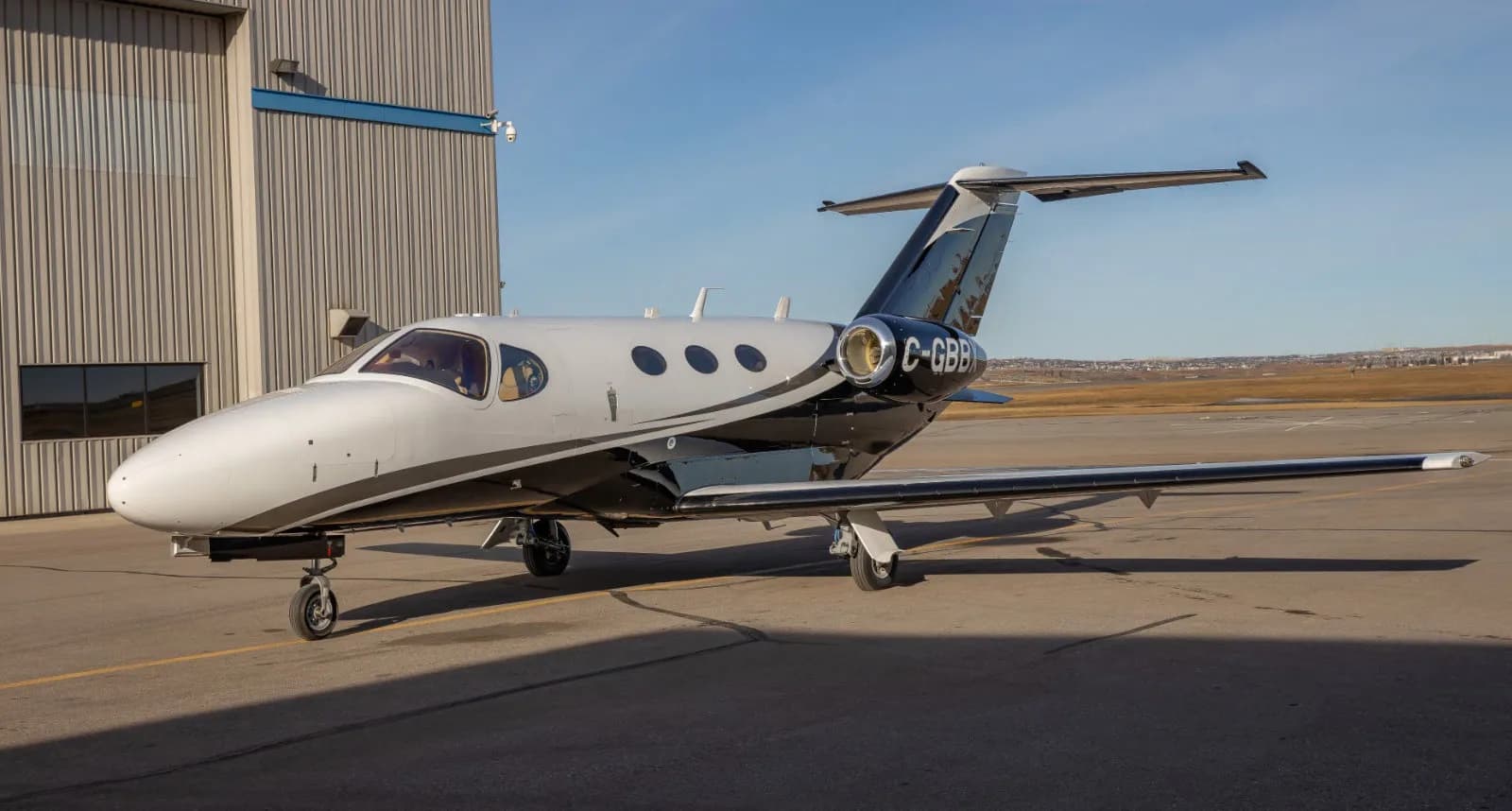 Cessna Citation Mustang aircraft with a black and white paint scheme on the tarmac.