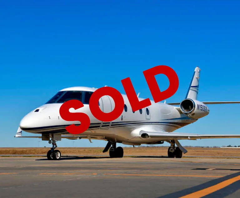 A white business jet with blue stripes and tail number N150GY is parked on an asphalt runway under a clear blue sky.