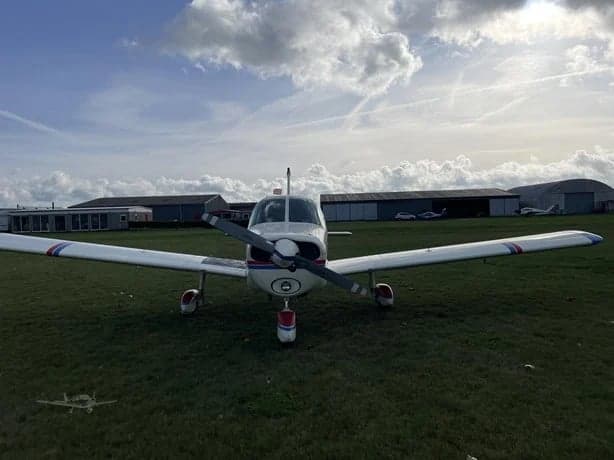 Front view of a Piper PA-28-181 Archer II aircraft, registration N735FL, parked on a grassy field.