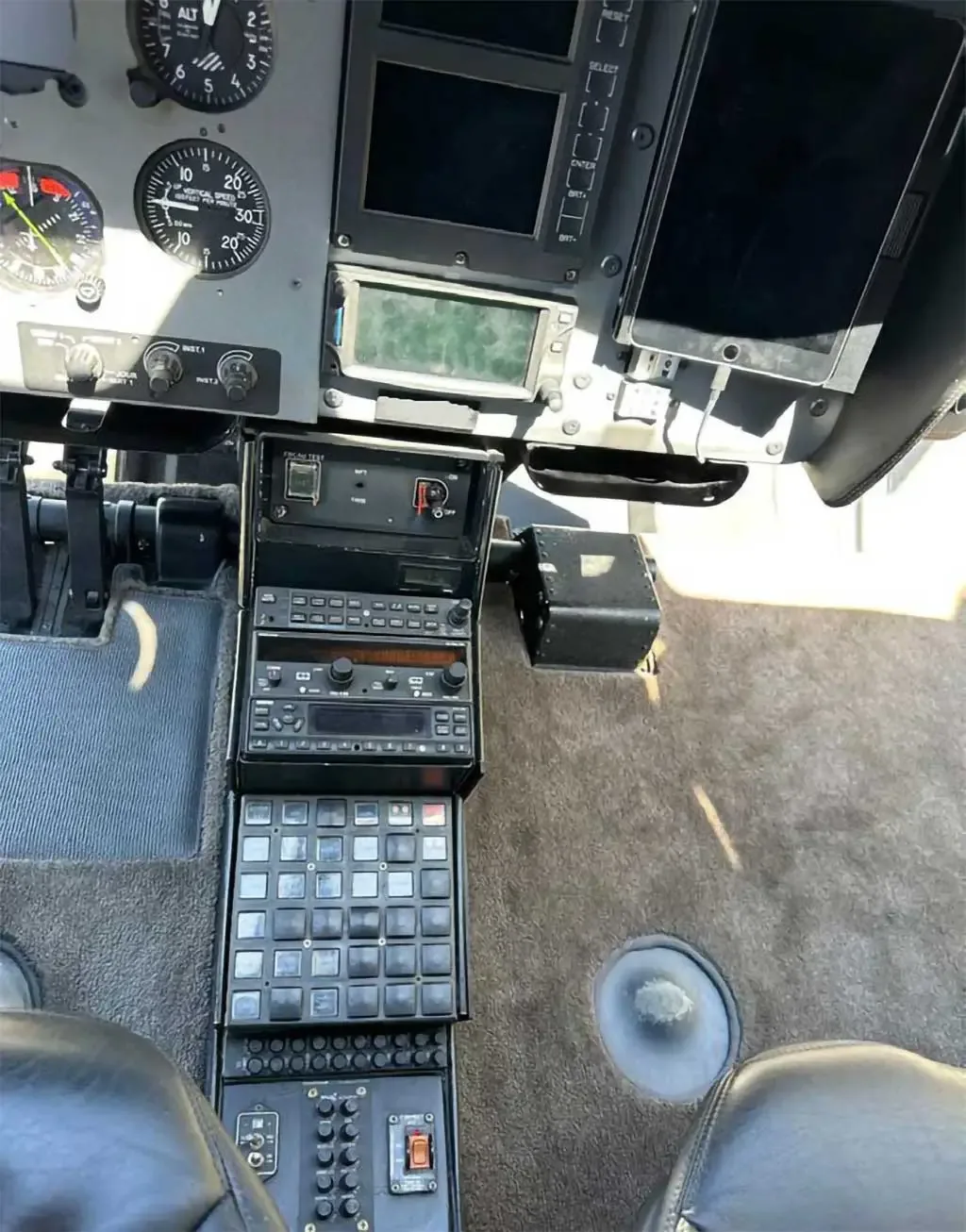 A detailed view of the helicopter's center console and lower instrument panel with various buttons and radios.