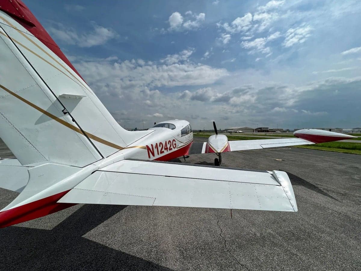 A rear-quarter view of the N1242G aircraft showing its tail and wing, parked on an airfield.