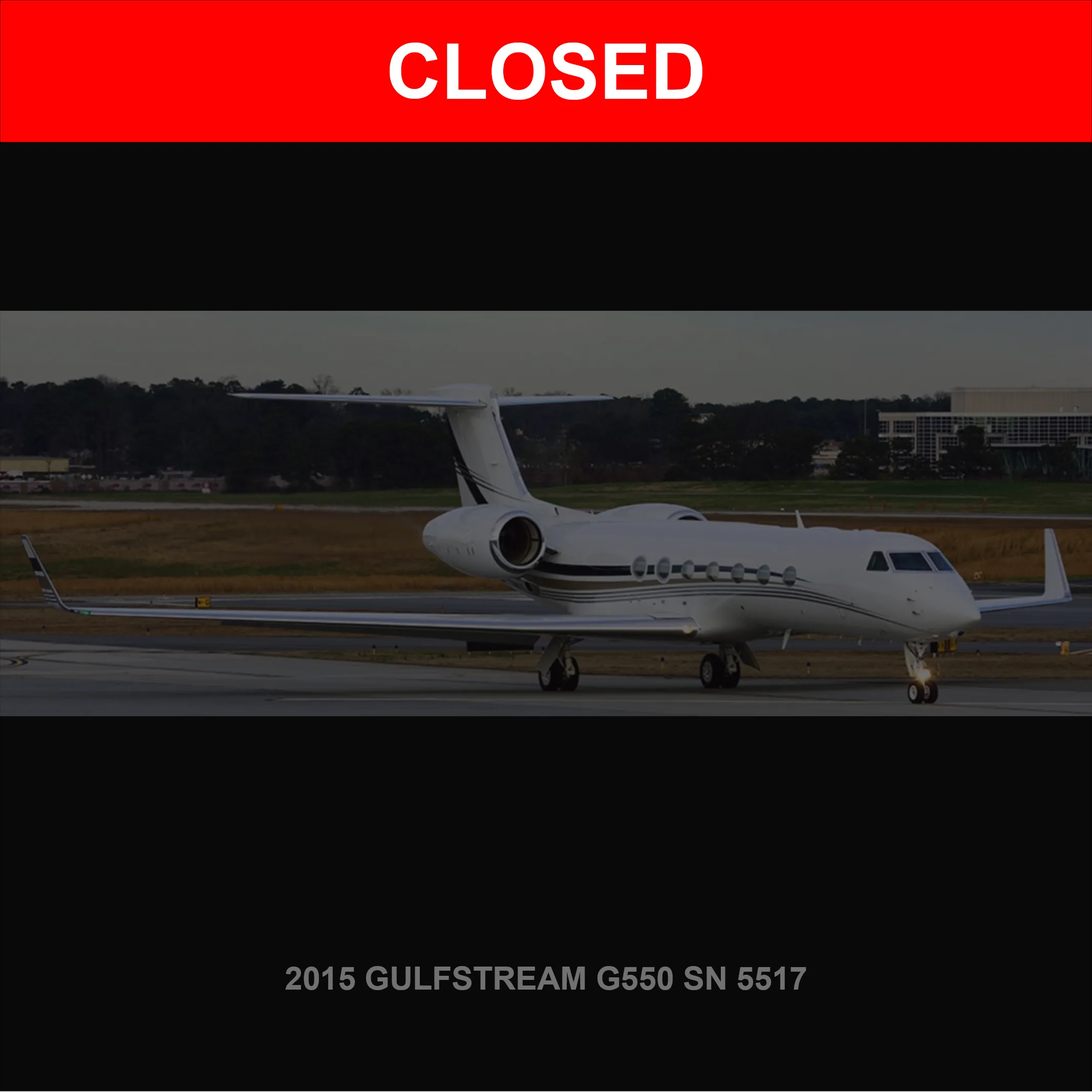 A white Gulfstream G550 business jet with dark accents is parked on an airport tarmac.