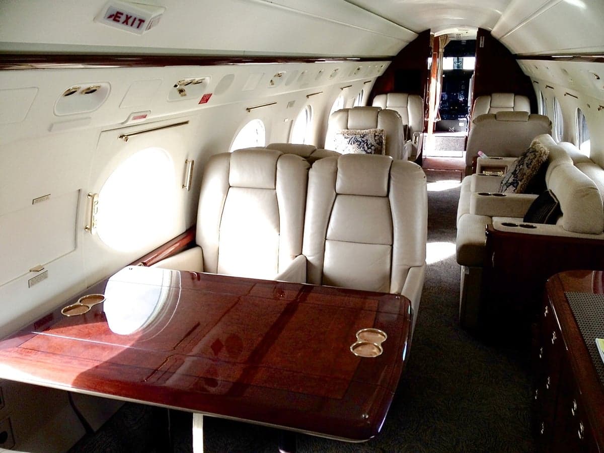 Interior of the aircraft featuring leather seats and a wooden table.