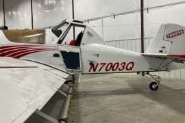 A white and red Air Tractor crop duster with the door open, showing the tail number N7003Q.
