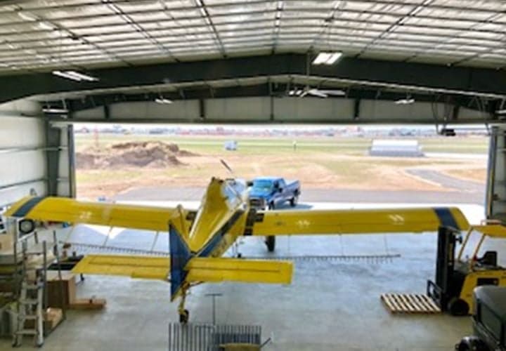 A yellow and blue Air Tractor AT-400 aircraft is parked inside a hangar.